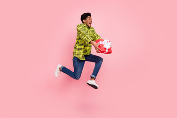 Wall Mural - Full length photo of millennial sweet brunette guy jump hold present wear shirt jeans sneakers isolated on pink background
