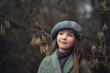 Photo of a beautiful girl with a gray beret in the forest.