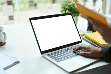 Poster - Photo of hands typing on a white blank screen computer laptop at the modern working desk.