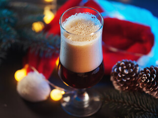 Wall Mural - A glass of beer on the Christmas table. Christmas tree branches, Santa hat and cones