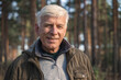 © Yakobchuk Olena - Old man wearing warm clothes enjoying walking at the forest near the trees