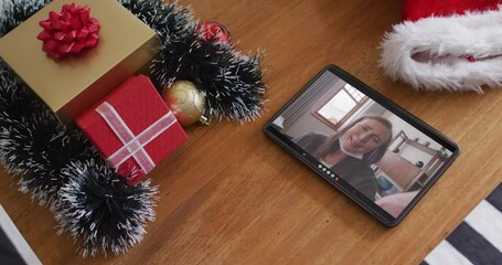 Canvas Print - Smiling caucasian woman wearing face mask on christmas video call on tablet