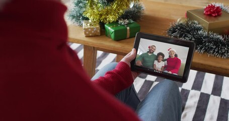 Poster - Caucasian man waving and using tablet for christmas video call with smiling family on screen