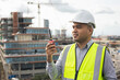 © Chanakon - Asian engineer handsome man or architect use radio communication with white safety helmet in city construction site . Standing on rooftop building construction at capital.