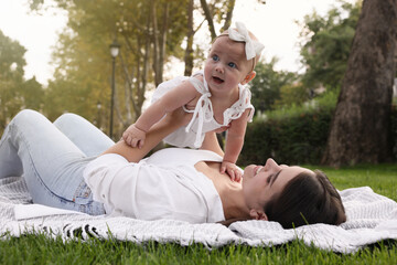 Canvas Print - Happy mother with adorable baby lying on green grass in park