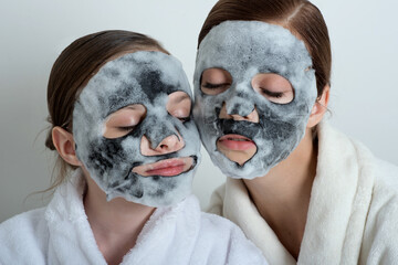 Wall Mural - Two girls with a bubble mask on their faces. Little girl and young woman enjoy spa treatments. SPA and wellness