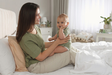 Wall Mural - Happy young mother with her cute baby on bed at home