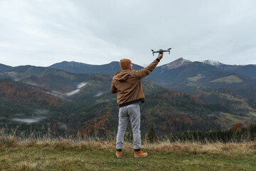 Wall Mural - Young man with modern drone in mountains, back view