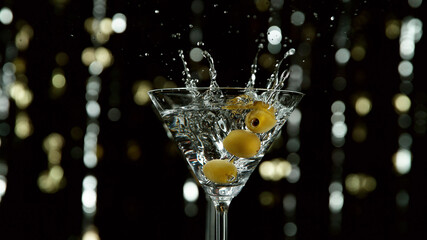 Freeze motion of falling olives into martini drink