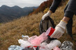 Woman with trash bag collecting garbage in nature, closeup