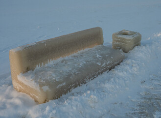 Wall Mural - Bench and trash can covered with ice due to a winter storm on the embankment of the city of Petrozavodsk in the Republic of Karelia on a frosty day