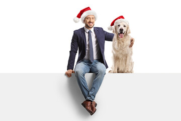 Sticker - Man sitting on a blank panel and hugging a retriever dog with a christmas santa hat