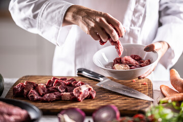 Wall Mural - Chef puts pieces of pork into a bowl to cook it