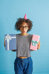 Wall Mural - Female person in party cone hat pouting lips and making funny face while holding two wrapped gift boxes