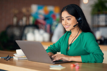 Cheerful indian woman having video call with colleagues, cafe interior