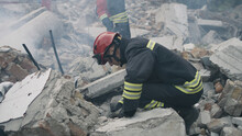 Pan Left View Of Male Emergency Workers Removing Concrete Rubble In Cloud Of Dust While Working On Ruins Of Destroyed Building After Disaster