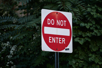 Do not enter traffic sign indicating that it is forbidden to go inside that street. Green tree background. Photo taken in a city from America, United States.