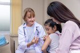 Fototapeta  - Pediatrician doctor doing vaccination of a little girl in hospital.