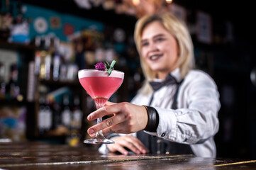 Girl bartender mixes a cocktail in the saloon