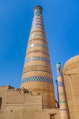 Minaret Islam Khoja against blue sky background. It is second tallest minaret in Central Asia, height is 56.5 m. Shot in Khiva, Uzbekistan