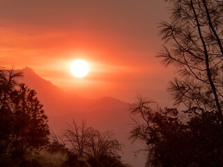 Sticker - Smoke enhanced sunrise, giving it unusual color, from wildfire in Southern Sierra Nevada Mountains, California, from drought stressed forest