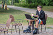 Businessman dressed in suit, shorts and rollers working with laptop outdoors