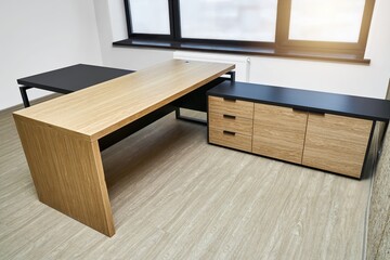 Large executive desk made of oak timber veneer with dark grey enamel in trendy minimal style stands in light spacious office