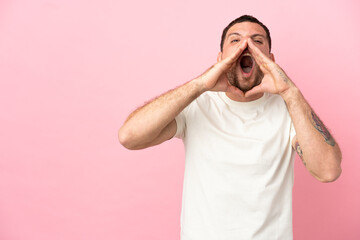 Young Brazilian man isolated on pink background shouting and announcing something