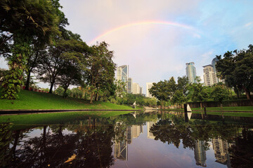 Sticker - Beautiful cityscape with rainbow in the sky. The pool in the city park.