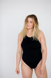 © kalinichenkod - Beautiful overweight woman in black swimsuit on grey background