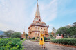 Travel by Asia. Young woman in hat and yellow dress walking near the Chalong buddhist temple on Phuket Island in Thailand.