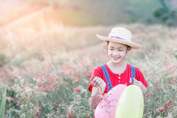 Wall Mural - Happy smile asian little girl with grass flowers in the wild field