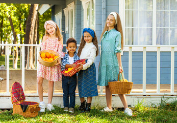 Wall Mural - Three girls and little boy stand by the porch with fruit baskets