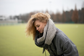 Wall Mural - Wunderbare Schöne Frau mit Blondem Haar  und Grauen Mantel in der Winter Zeit in Berlin Grüner Sport Platz