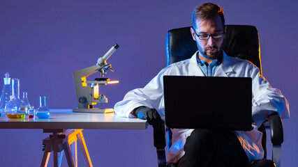 Poster - a scientist enters the results of chemical experiments into a laptop. chemist in the lab. a man runs