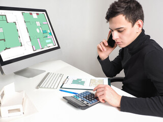 Poster - The architect sits at his Desk and communicates on a mobile phone. A man works with the floor plans. Approval of alterations in buildings. Engineer in the field of construction.
