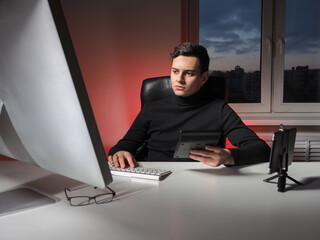 Poster - A man at a remote job. The young man works from home. Remote work concept. Freelancer in his home office. Young businessman in the office.