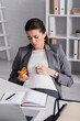 © LIGHTFIELD STUDIOS - pregnant woman holding jar with pills in office.