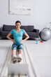 © LIGHTFIELD STUDIOS - smiling pregnant woman in sportswear exercising near laptop in living room.