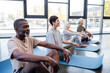 © LIGHTFIELD STUDIOS - Senior woman meditating on yoga mat near interracial people in gym.