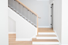 A Staircase Going Up With Natural Wood Steps And Handrails, White Risers, And Wrought Iron Spindles.
