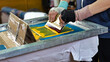 male hands with a squeegee. serigraphy production selective focus photo. printing images on clothes by silk screen method in a design studio