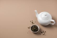 White Teapot With A Bowl Of Green Tea On A Beige Background Top View