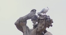 On The Head Of The Sculpture Sits A White Bird
