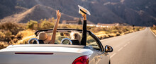 Dreams Come True! Two Happy Young Girls Driving Cabrio Car During Vacation Road Trip In Mountains, Making Memories And Having Fun Together. Freedom Concept. Happiness. Tourist. Wanderlust.