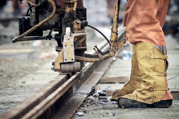 Poster - Construction worker using machine for steel train tracks.