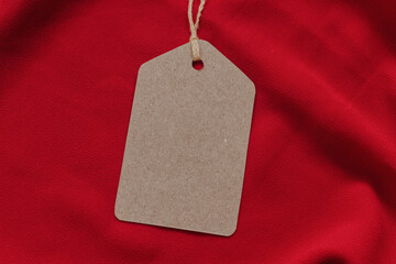 Wall Mural - Price tag or blank cardboard label with thread isolated on the red cloth. Great for clothing or fashion mockups.