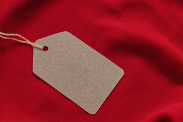 Wall Mural - Price tag or blank cardboard label with thread isolated on the red cloth. Great for clothing or fashion mockups.