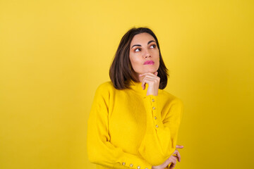 Wall Mural - A young woman in a cozy yellow sweater on a background with a bright pink lip gloss looks to the side with inspiration, dreamily, pensively