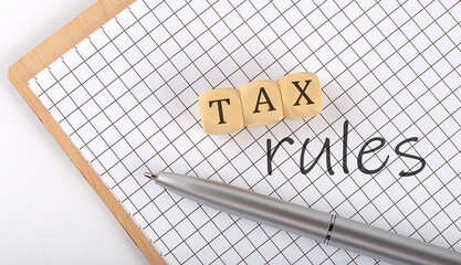 Poster - TAX RULES text concept written on the wooden cubes blocks and notebook